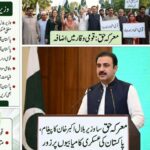 پاکستانی وزیر بلال اکبر خان معرکہ حق کی پہلی سالگرہ پر خطاب کرتے ہوئے، قومی پرچم اور عسکری پس منظر کے ساتھ تقریب کا منظر۔