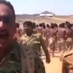 "صحرائی علاقے میں فوجی وردی میں ملبوس یمنی یمنی فوج کا منظم آپریشن: الجوف میں حوثیوں کی اسلحہ سپلائی لائن منقطع فوجی جوان نعرے لگاتے ہوئے آگے بڑھ رہے ہیں، پس منظر میں مزید فوجیوں کا بڑا جتھہ صحرا میں مارچ کر رہا ہے۔"